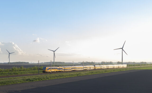 intercity-train-of-the-dutch-railways-driving-in-springtime-landscape-with-wind-turbines